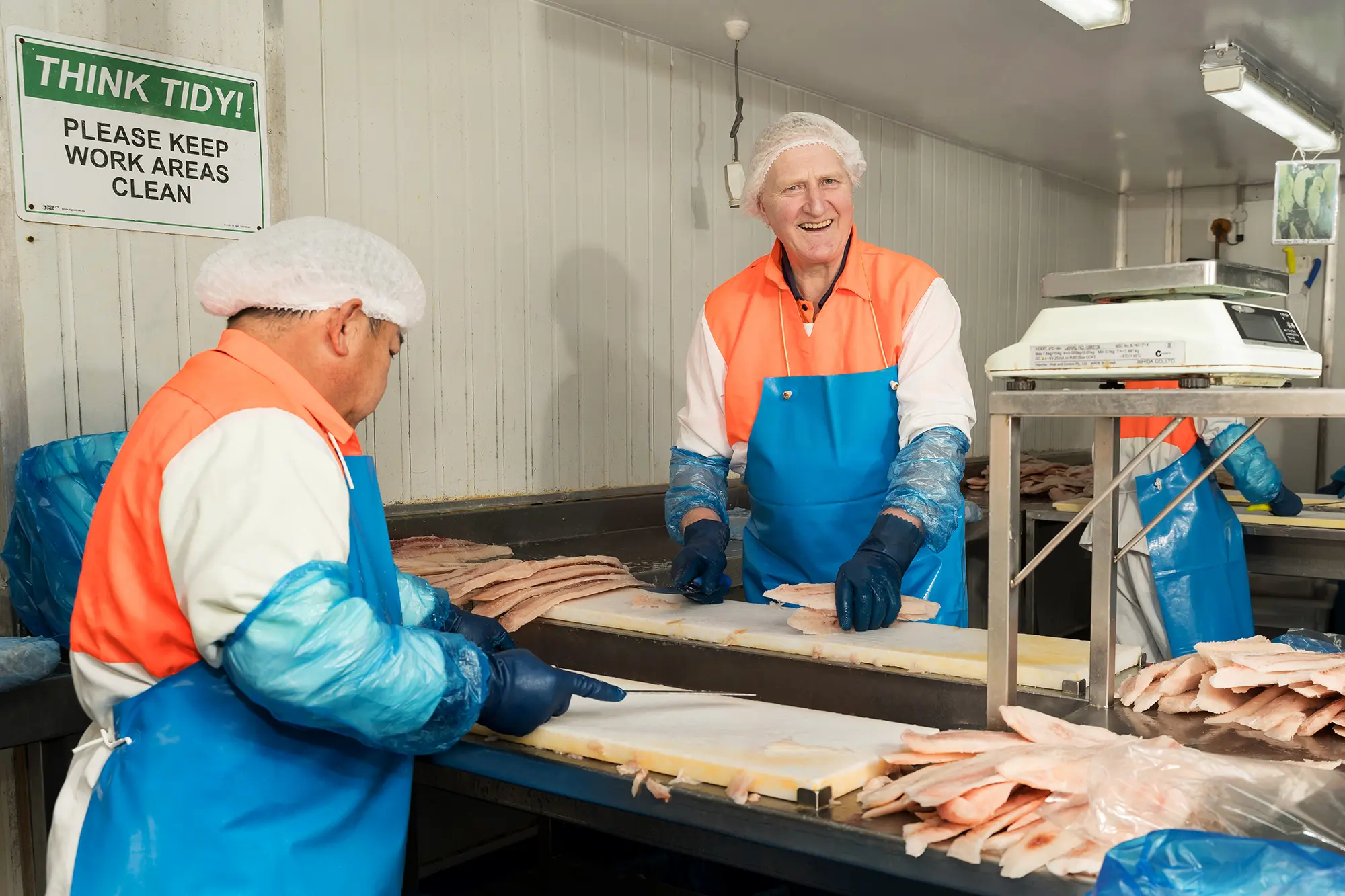 Team members filleting fish on the production floor
